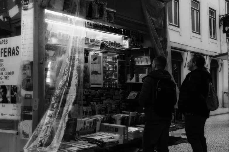 two people stand outside of a convenience store