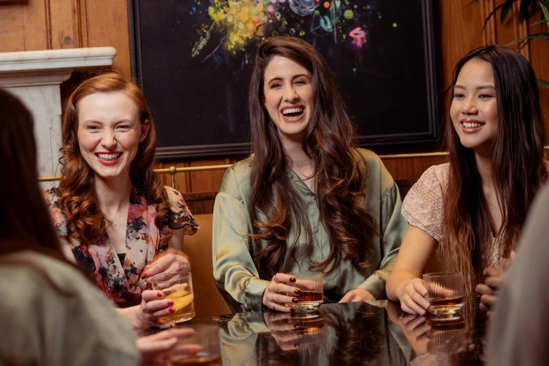 three girls sit and drink together at the bar