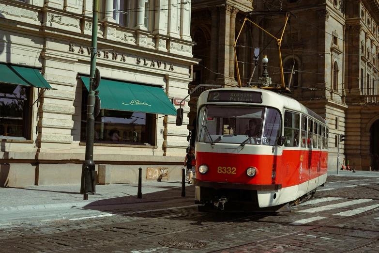 a red and white trolley passing under buildings