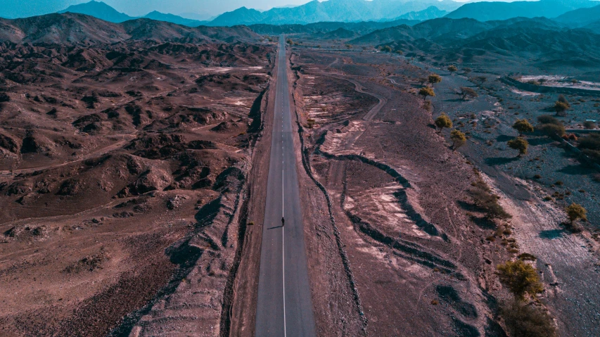 an aerial view of a highway that has mountains in the background