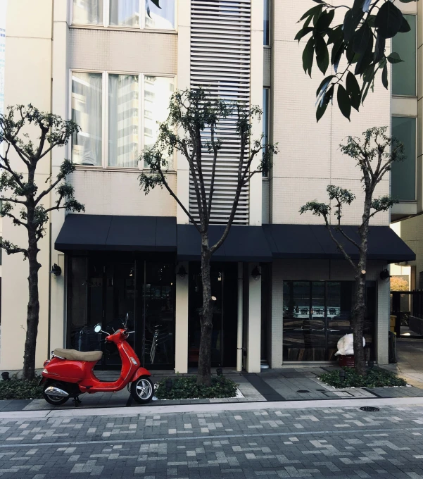 the scooter is parked outside of the store in front of the building