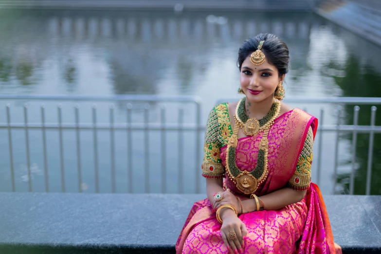 woman in indian clothing sitting on a ledge near water