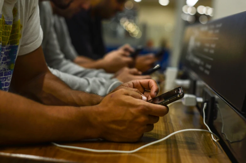 a group of people sitting next to each other holding cell phones