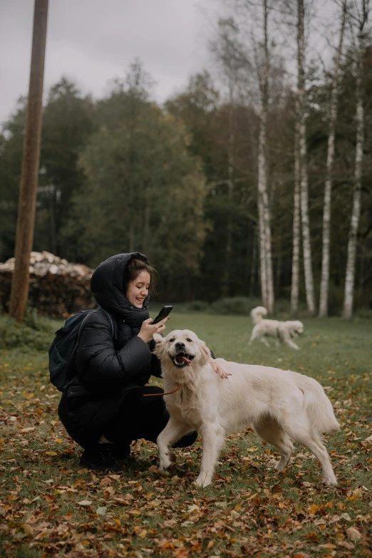 a woman petting a white dog and some brown leaves