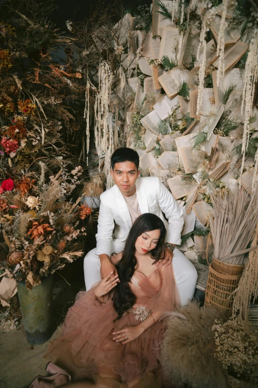 a man and woman dressed in white posing in a plant display