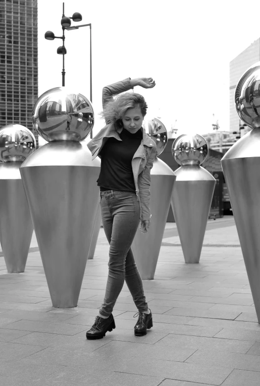 a black and white po of a woman walking next to several art sculptures