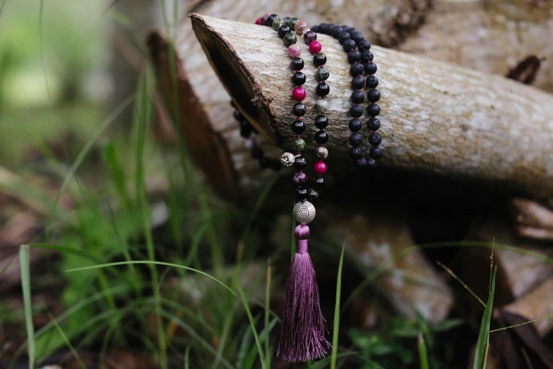 a wooden piece of wood with a tasseled and beaded necklace