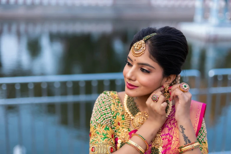 an indian woman poses in traditional saree with her hand in the ear