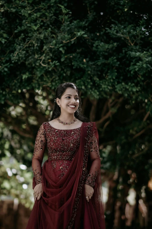 a young woman wearing a maroon dress and gold jewelry