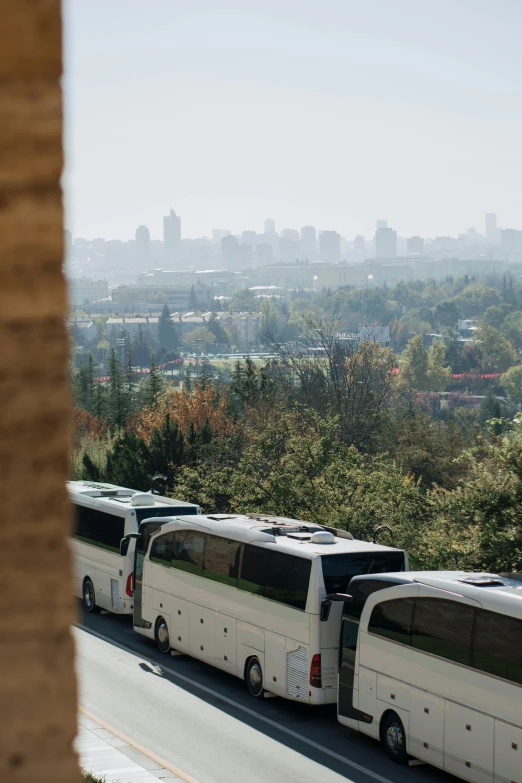 three buses are lined up in front of a building on the road