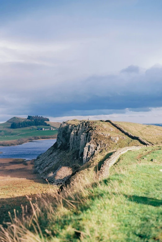 a large brown and green hill near a lake