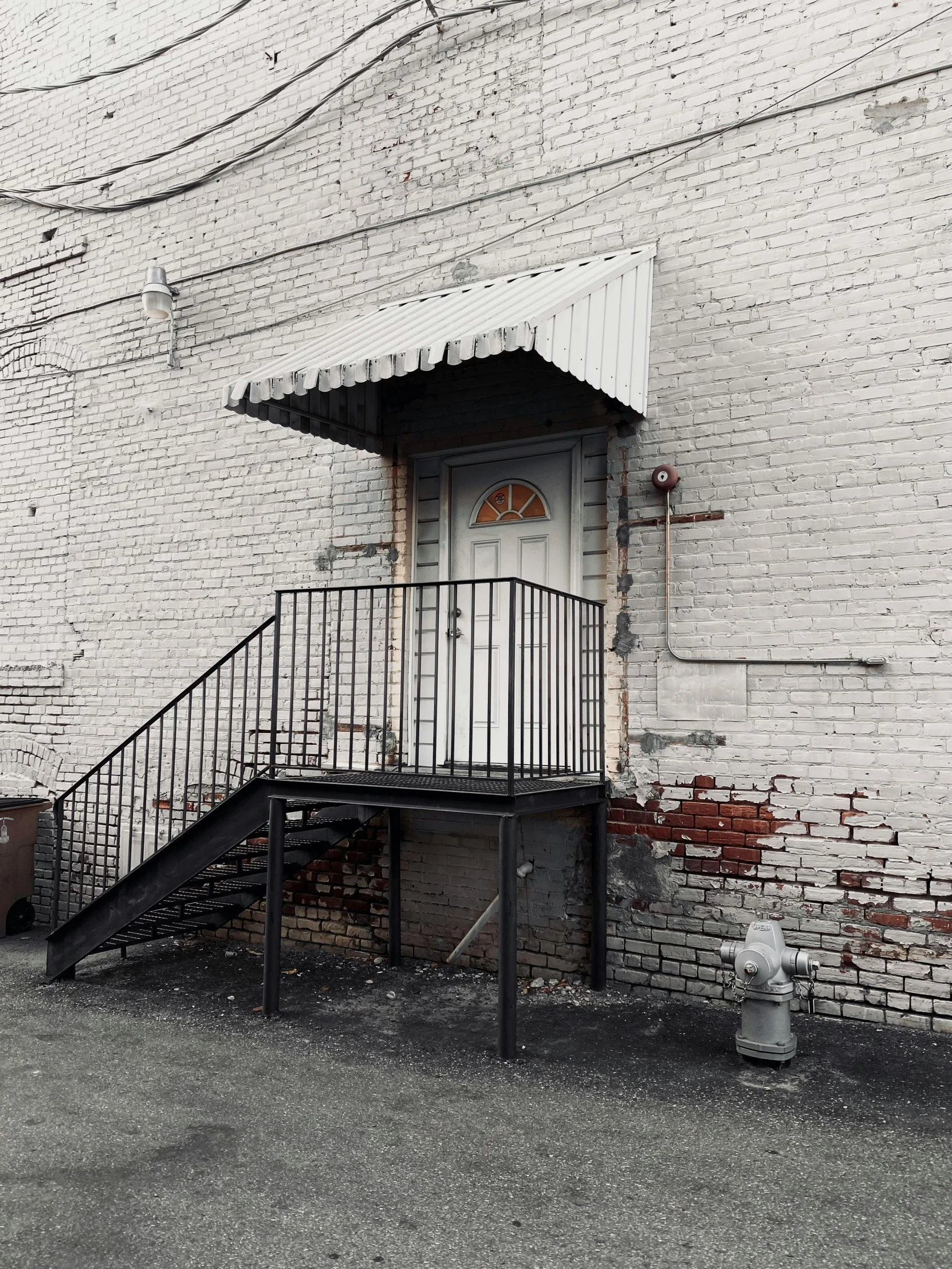 the stairs to a white door lead up to the front of a brick building