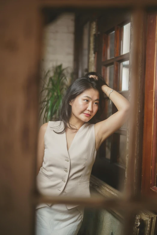 a woman in a white top leaning up against a window