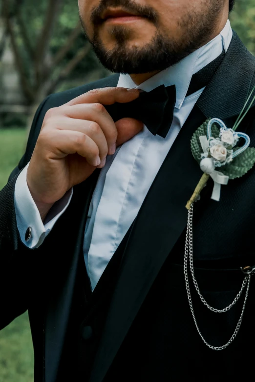 a man in a tuxedo adjusting his jacket collar