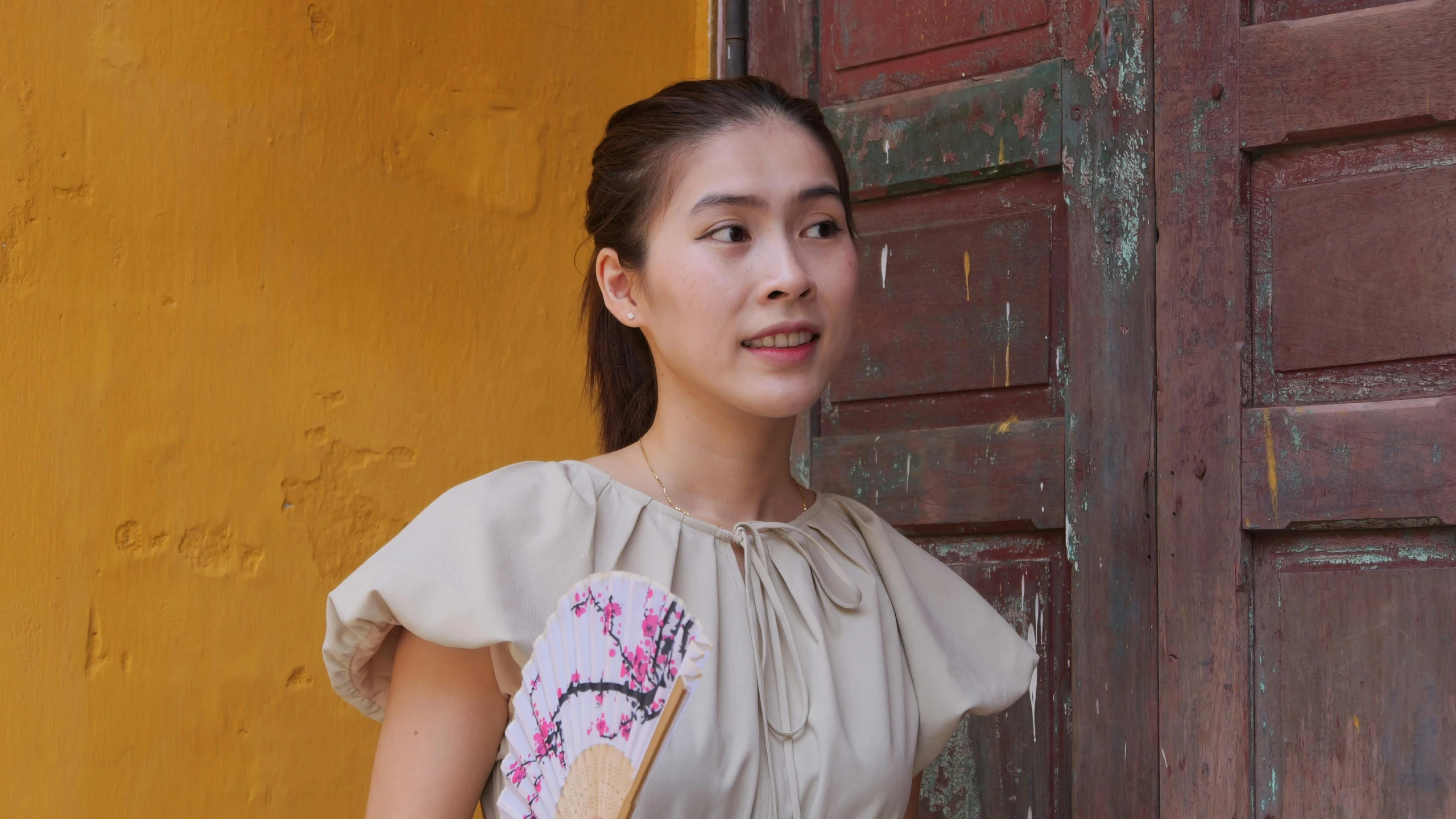 young woman posing for picture next to an old building