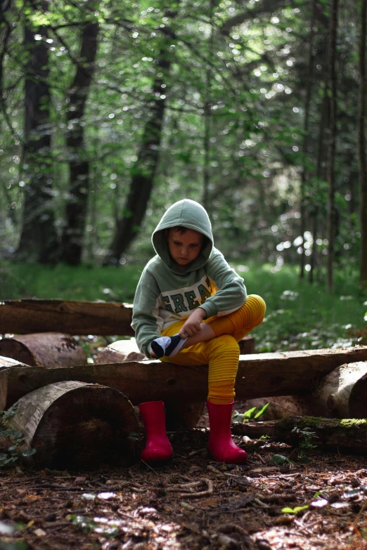 a young person sitting on logs in the woods