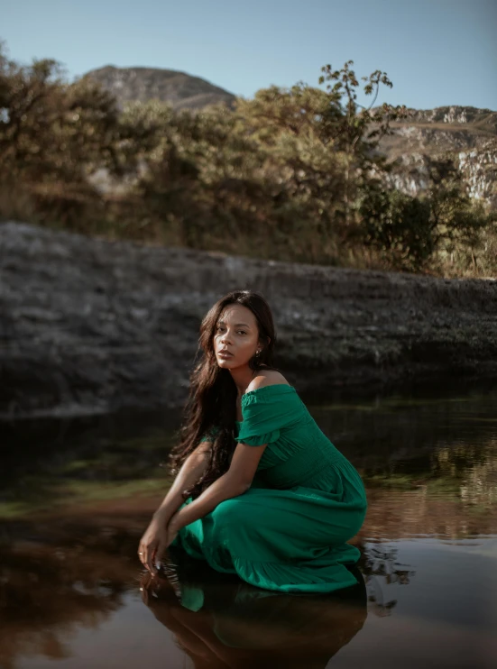 a woman in a green dress is sitting in the water