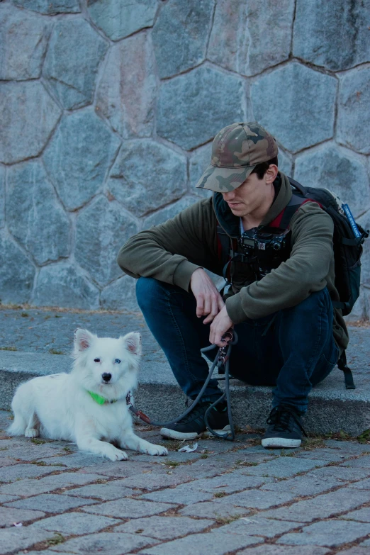 a man and a white dog sitting next to each other on a sidewalk