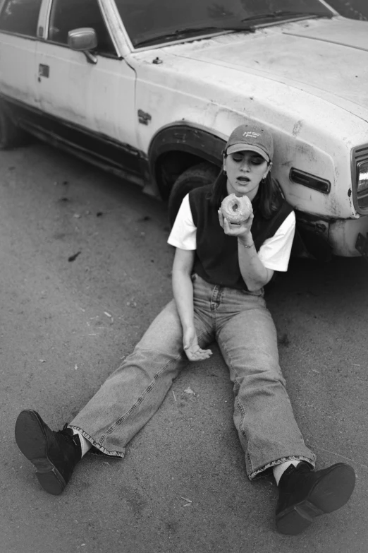 a man laying on the ground next to a car and pointing at his camera