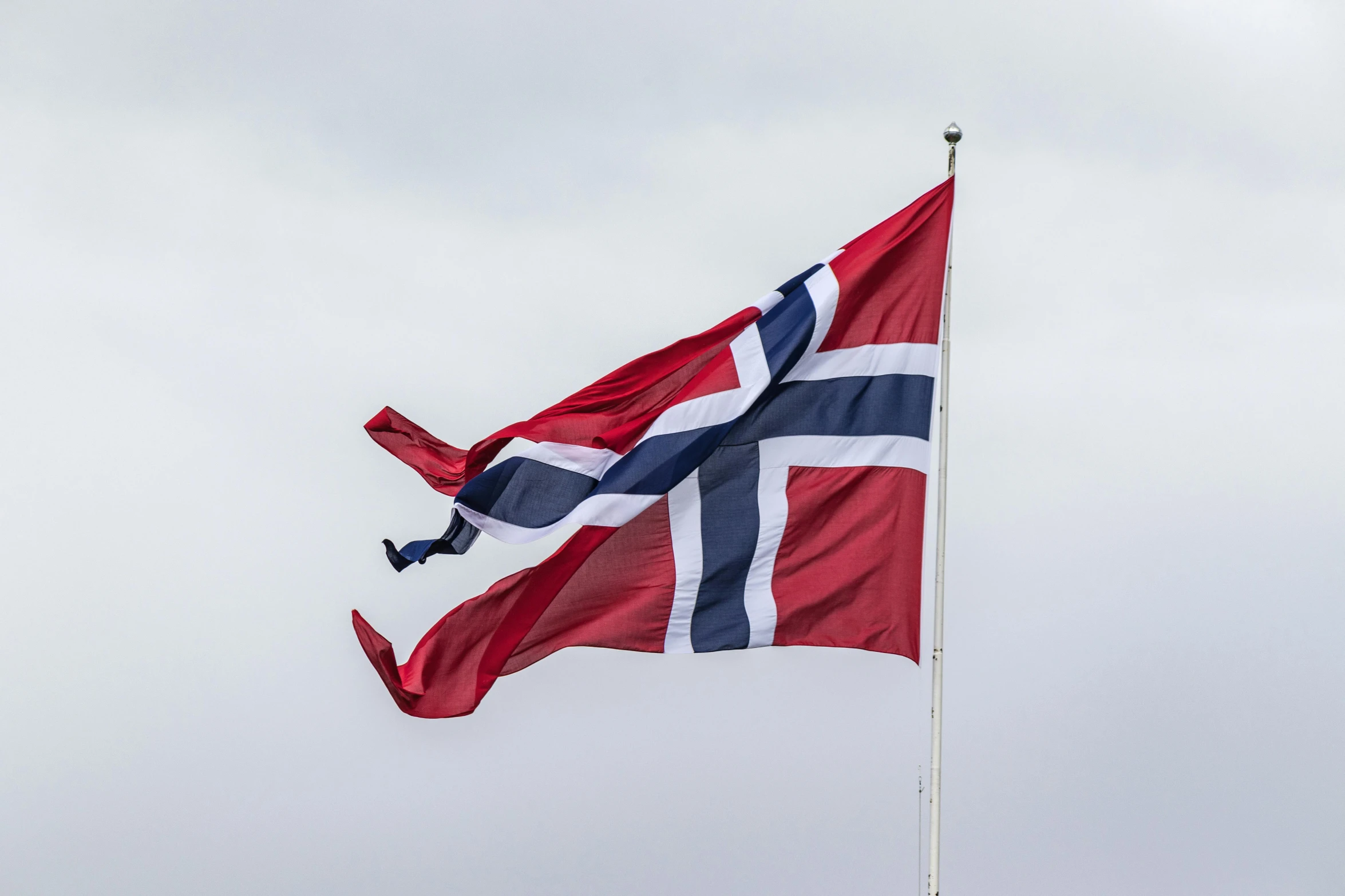 a norway flag is flying on a cloudy day