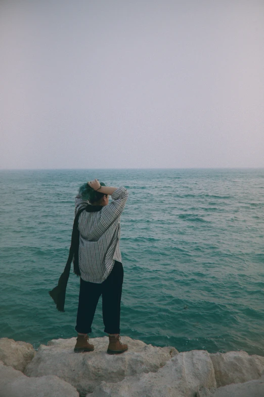 a woman standing near the ocean while taking pos