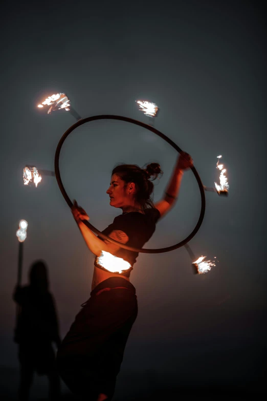 a young woman holding a hula hoop with her hands and lights on it