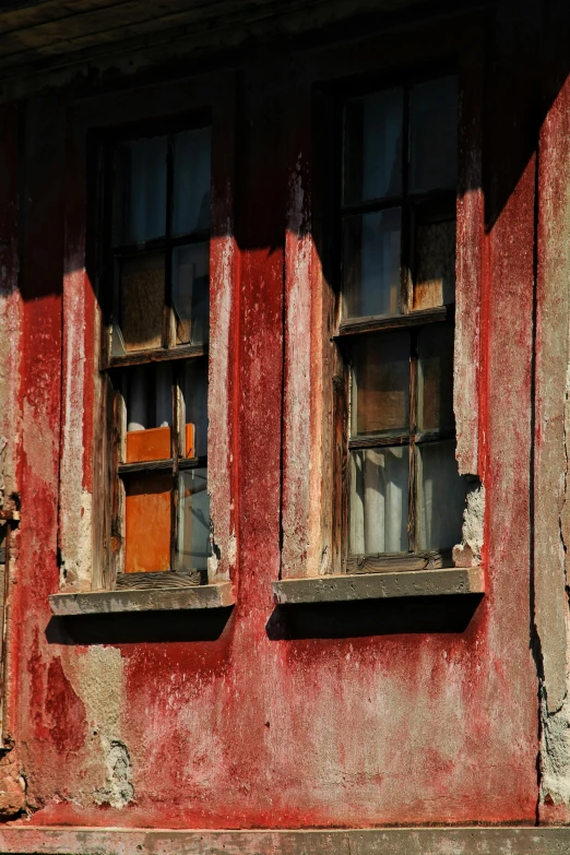 two windows are seen in an old red building