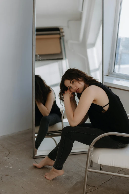 a woman sits in front of a mirror holding her hands up