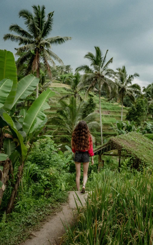 a woman in shorts walking towards lush green field