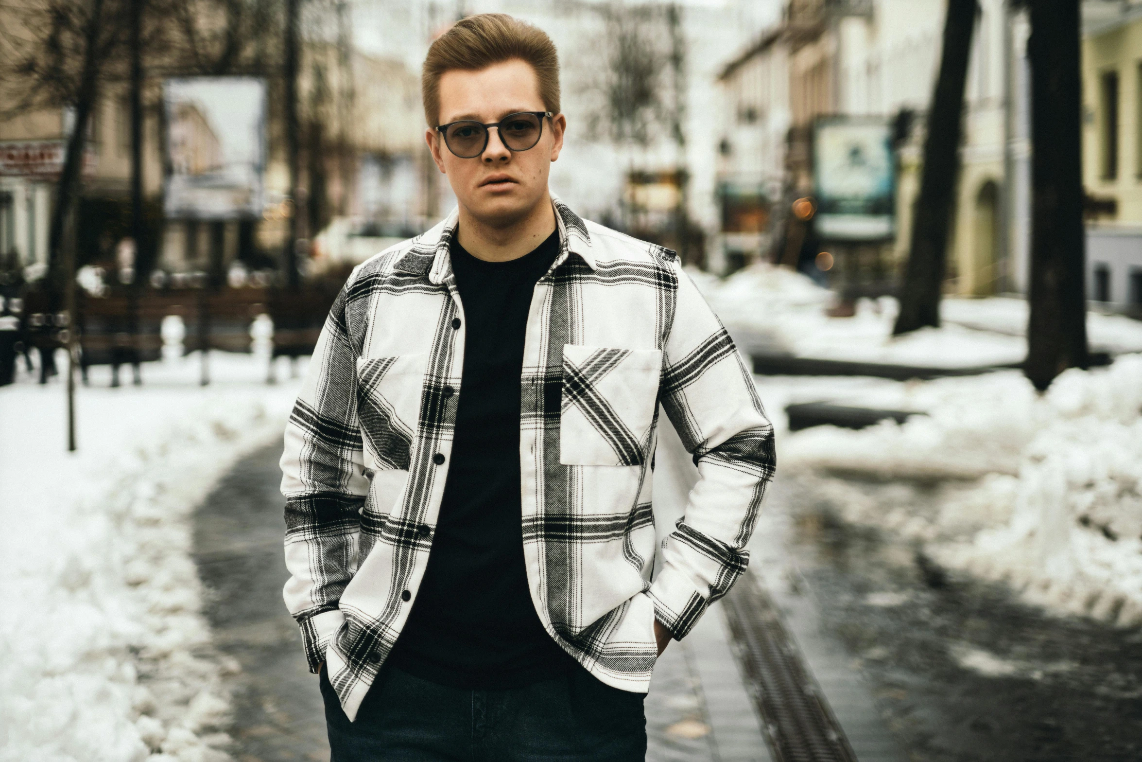 man with sunglasses stands in snowy street