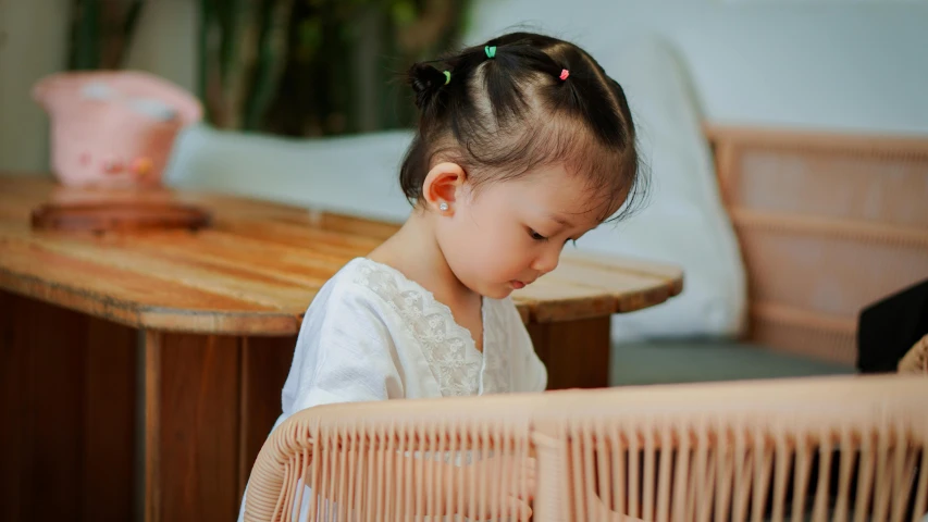 a small girl sitting at a table next to a bird cage