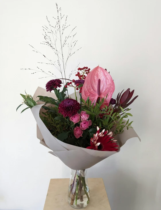 a vase filled with purple and pink flowers on top of a wooden table