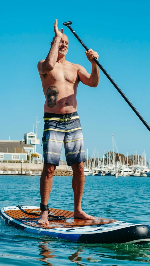 man on a surfboard standing up with pole