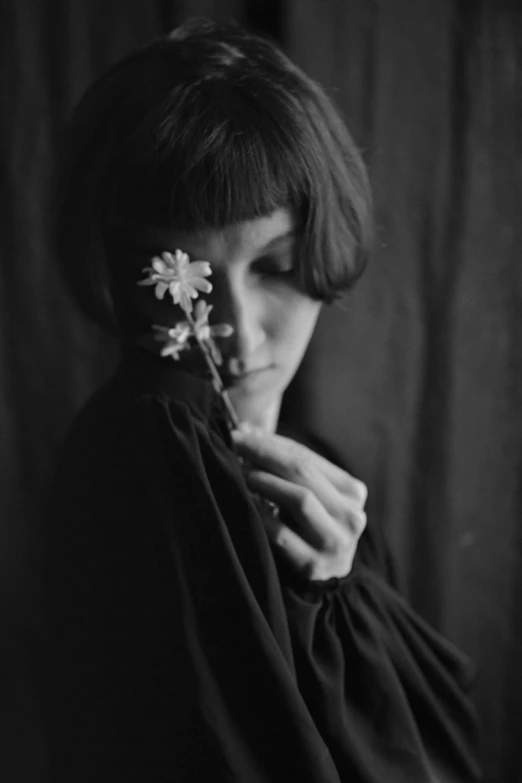 the lady is wearing a black dress and holding a flower