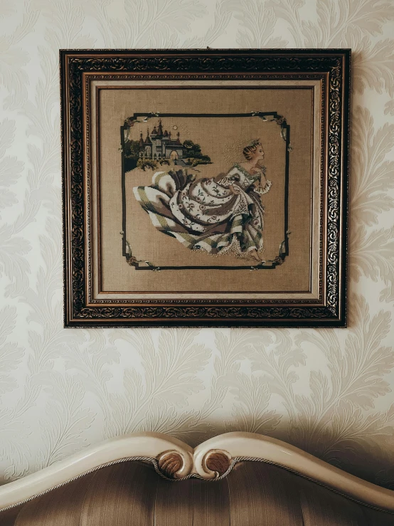 a vintage frame hanging above a fancy bed