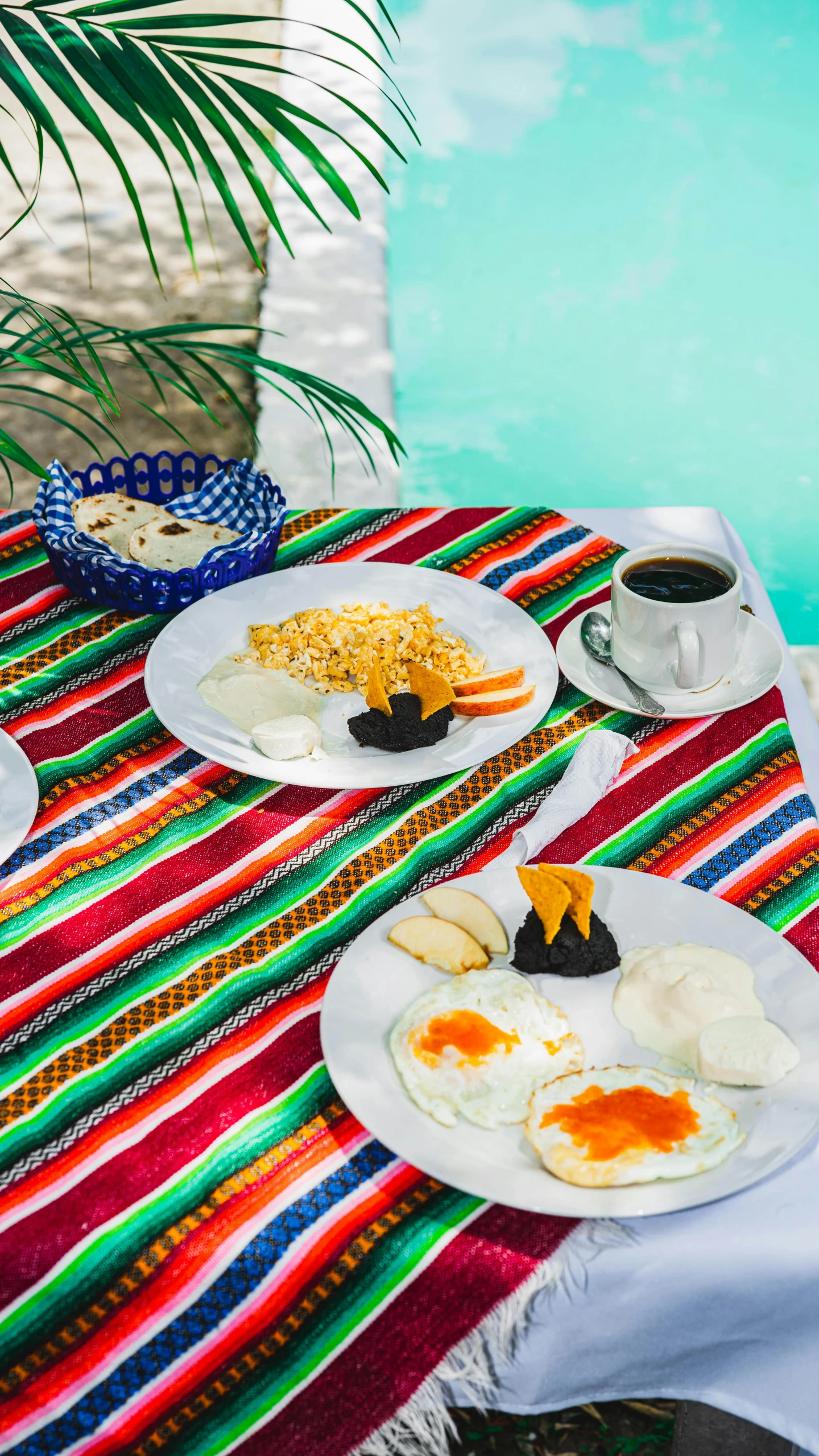 a table topped with plates of food next to a swimming pool