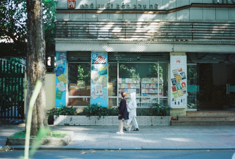 a couple walks down the street past shops