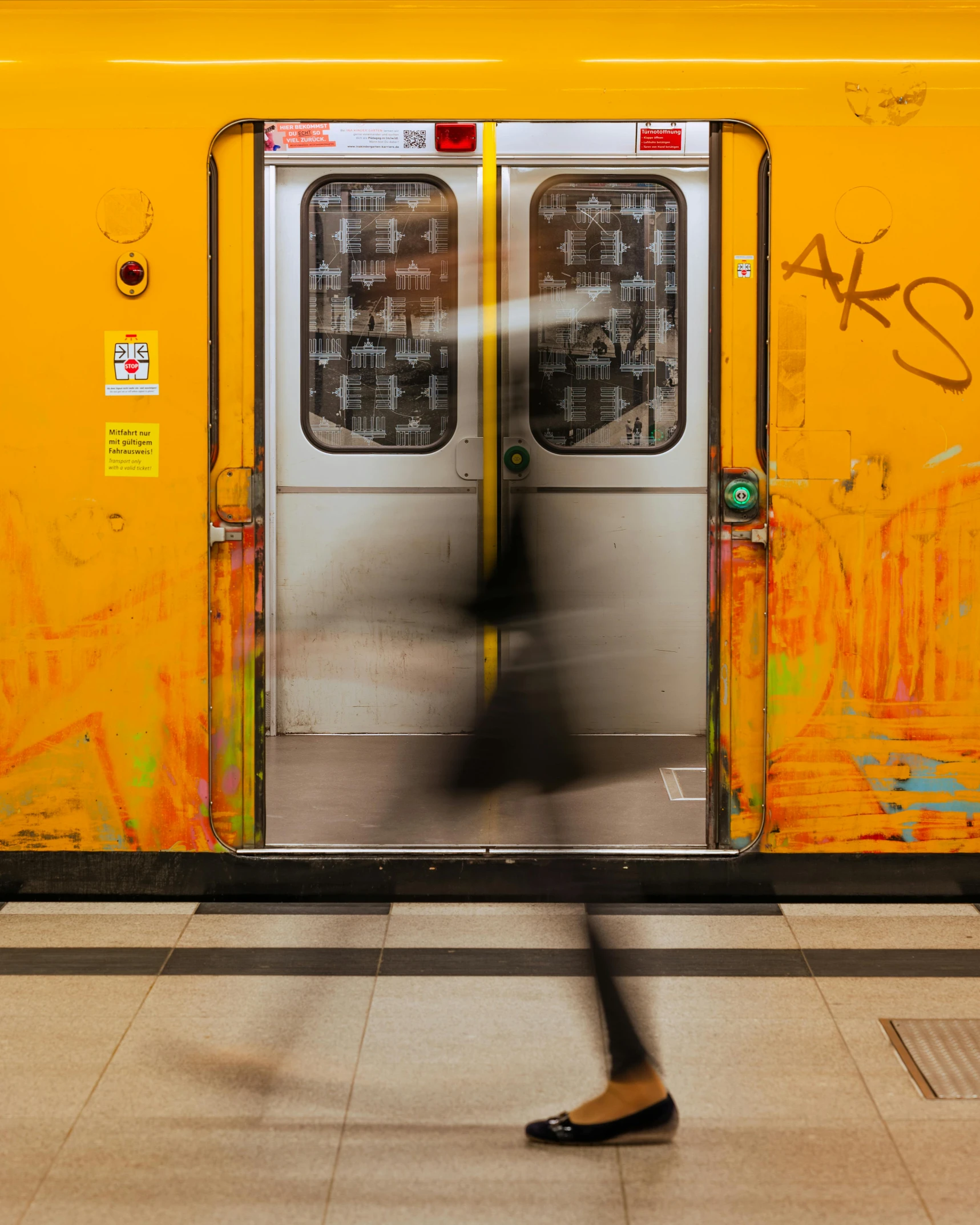 a yellow wall with graffiti and people walking in it