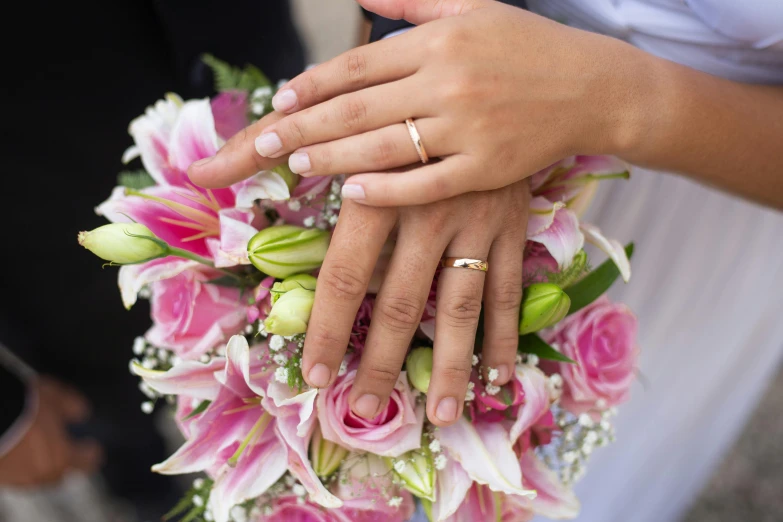 two hands hold a bouquet of flowers as if they were married