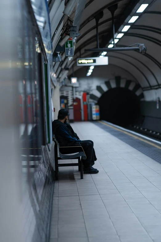 a man is sitting on a bench next to a train