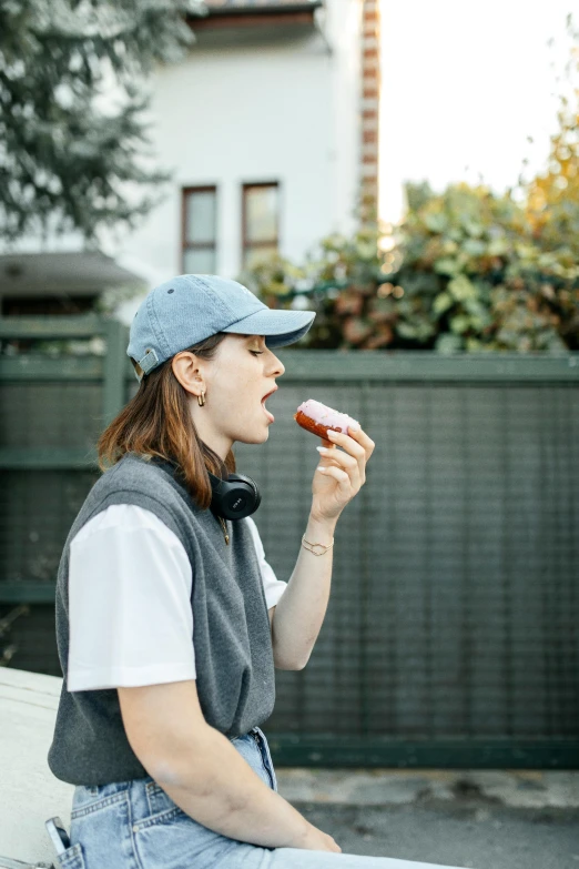 a woman wearing a baseball cap eating a donut