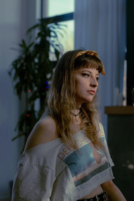 a young lady standing in front of a window wearing an open shirt