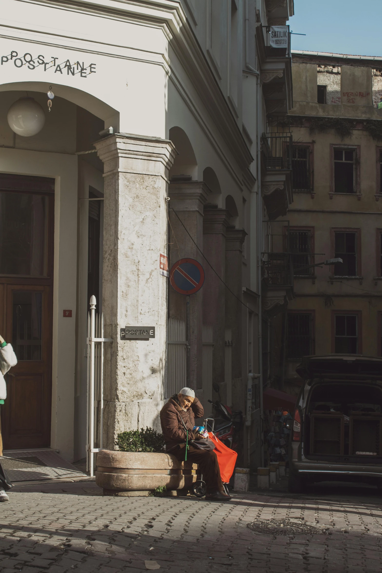 a couple of people sitting on a bench on the sidewalk