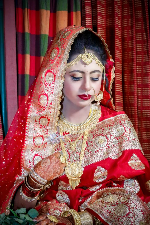 a woman in red and gold with red makeup, red shawl, and indian hairs