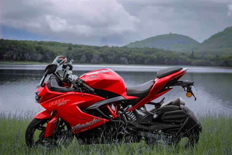 the motorcycle is parked by the water by the grass