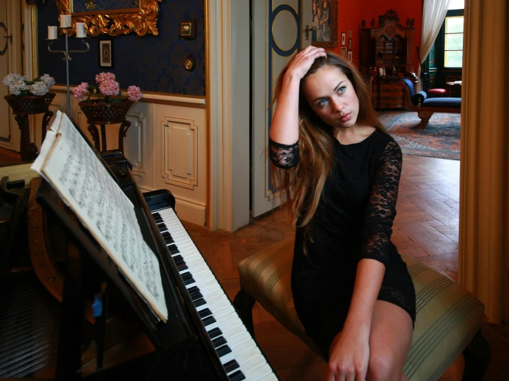 a woman wearing a black dress and sitting at a piano