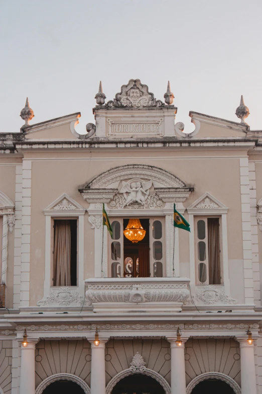 an old building is decorated with two flags and two clocks