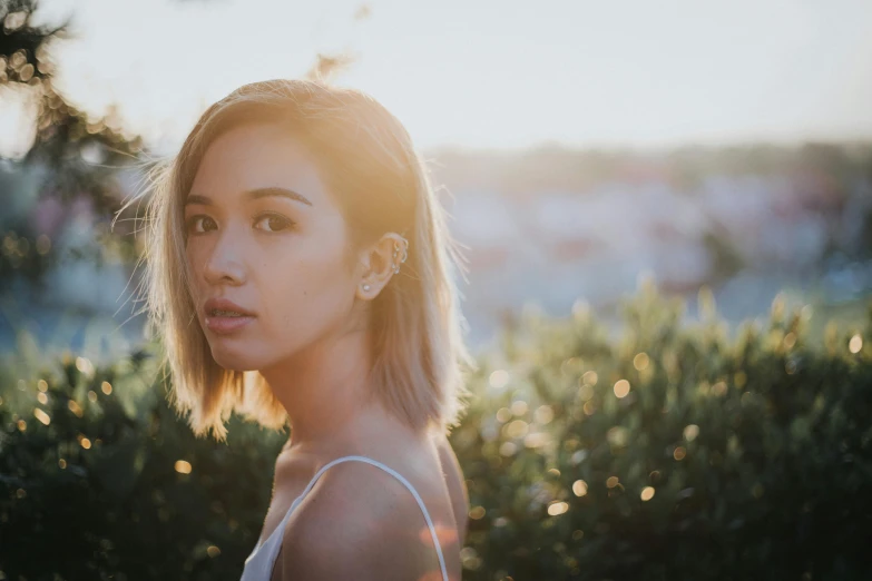 a young woman standing in front of a bush