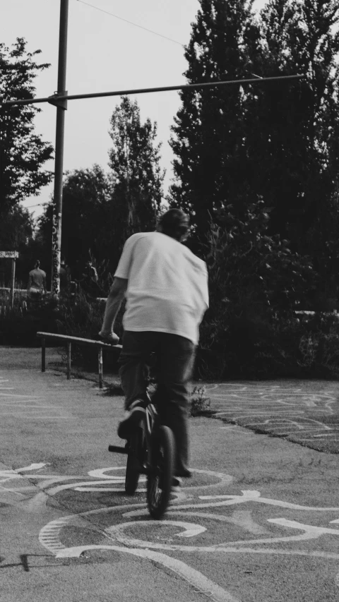 a black and white pograph of a man on a bike in the street
