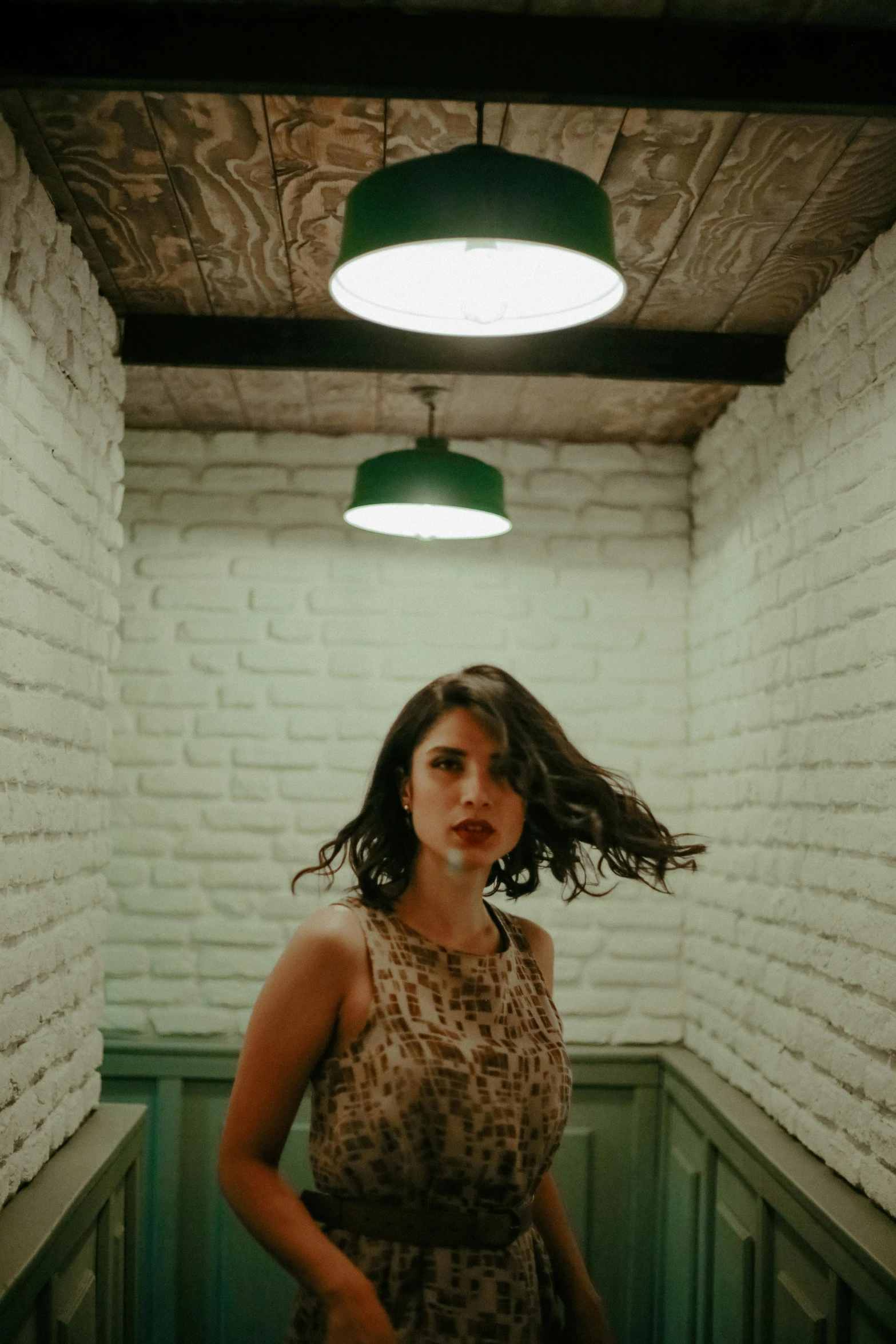 a woman is standing in the corner of a room with lights hanging from ceiling